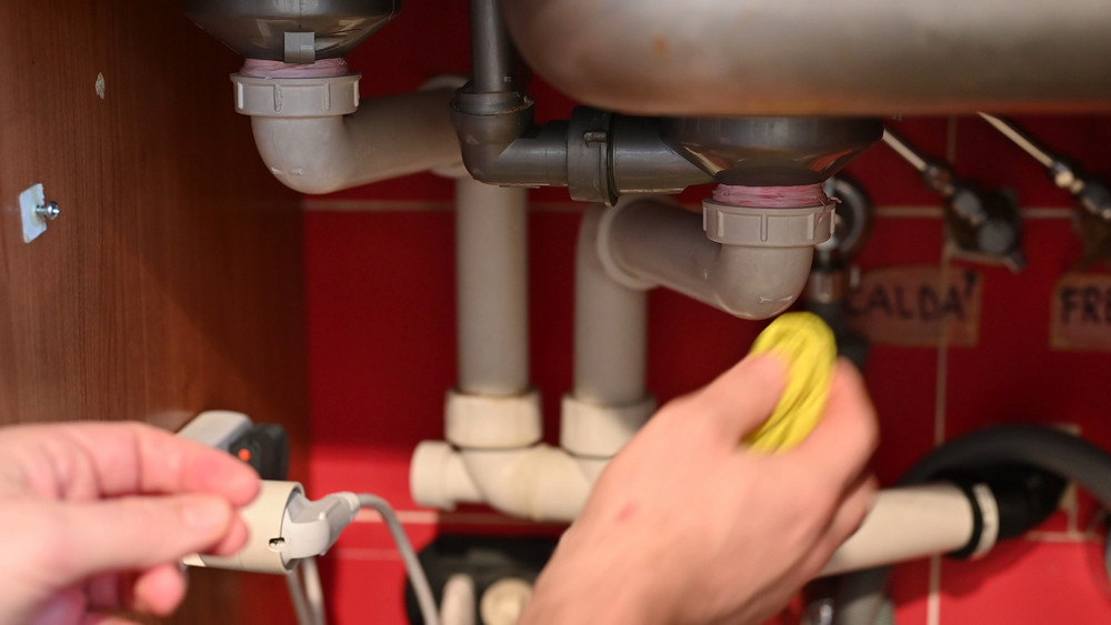 Drain cleaning services clearing clogged pipe to prevent water damage